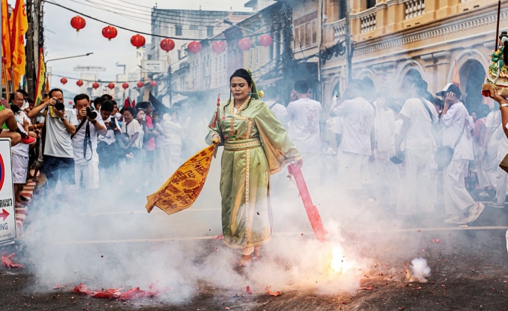 A devotee with piercings at the mouth dancing over firecreackers